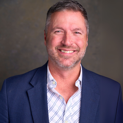 A professional headshot of Art Wood. He is wearing a navy blue blazer over a patterned button-up shirt against a neutral backdrop.