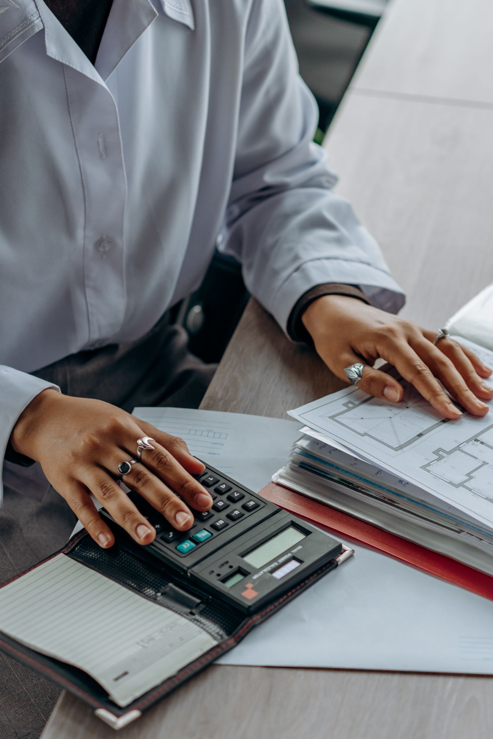 Hands using a calculator alongside financial documents.