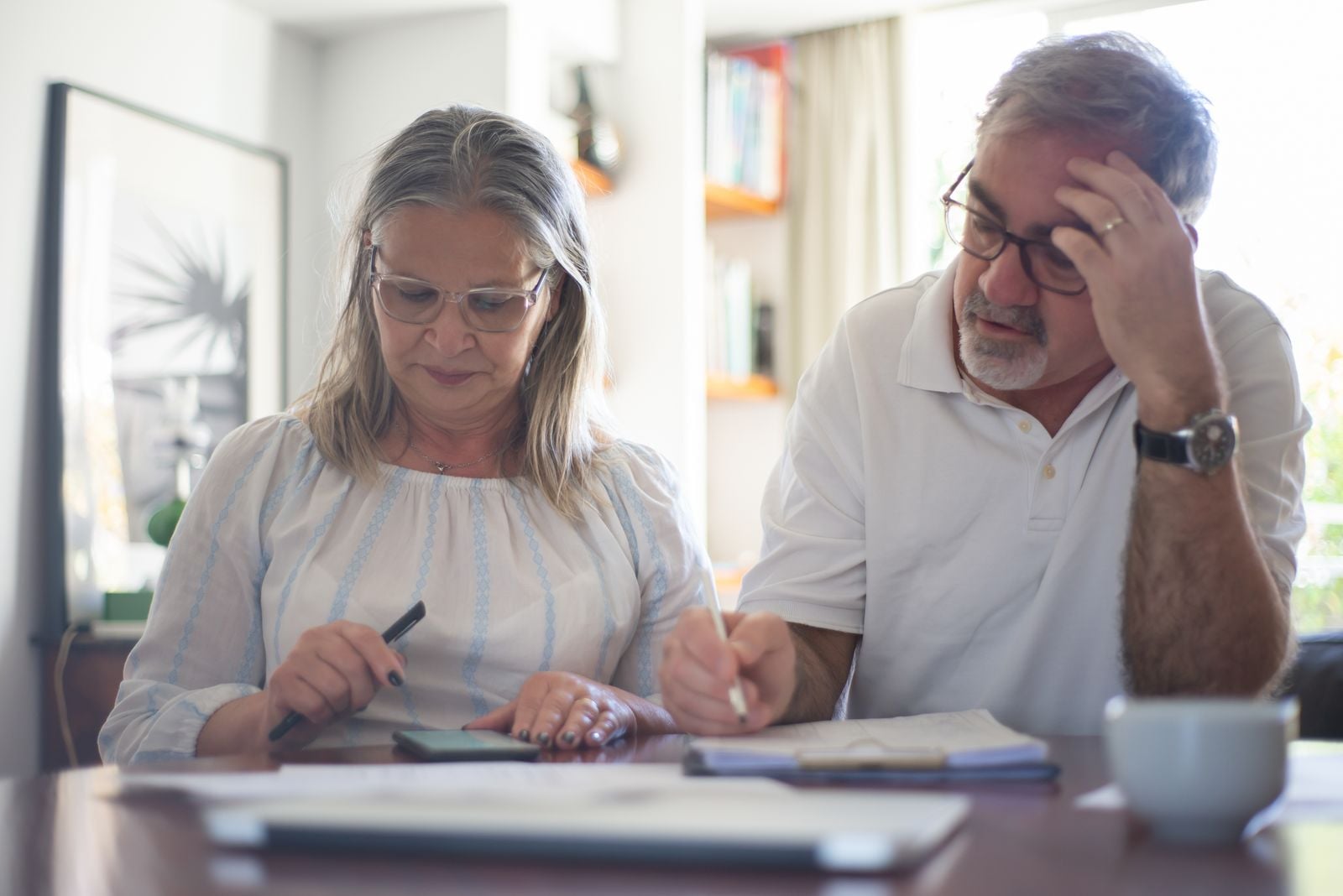 Older couple reviewing documents and making notes at a desk.