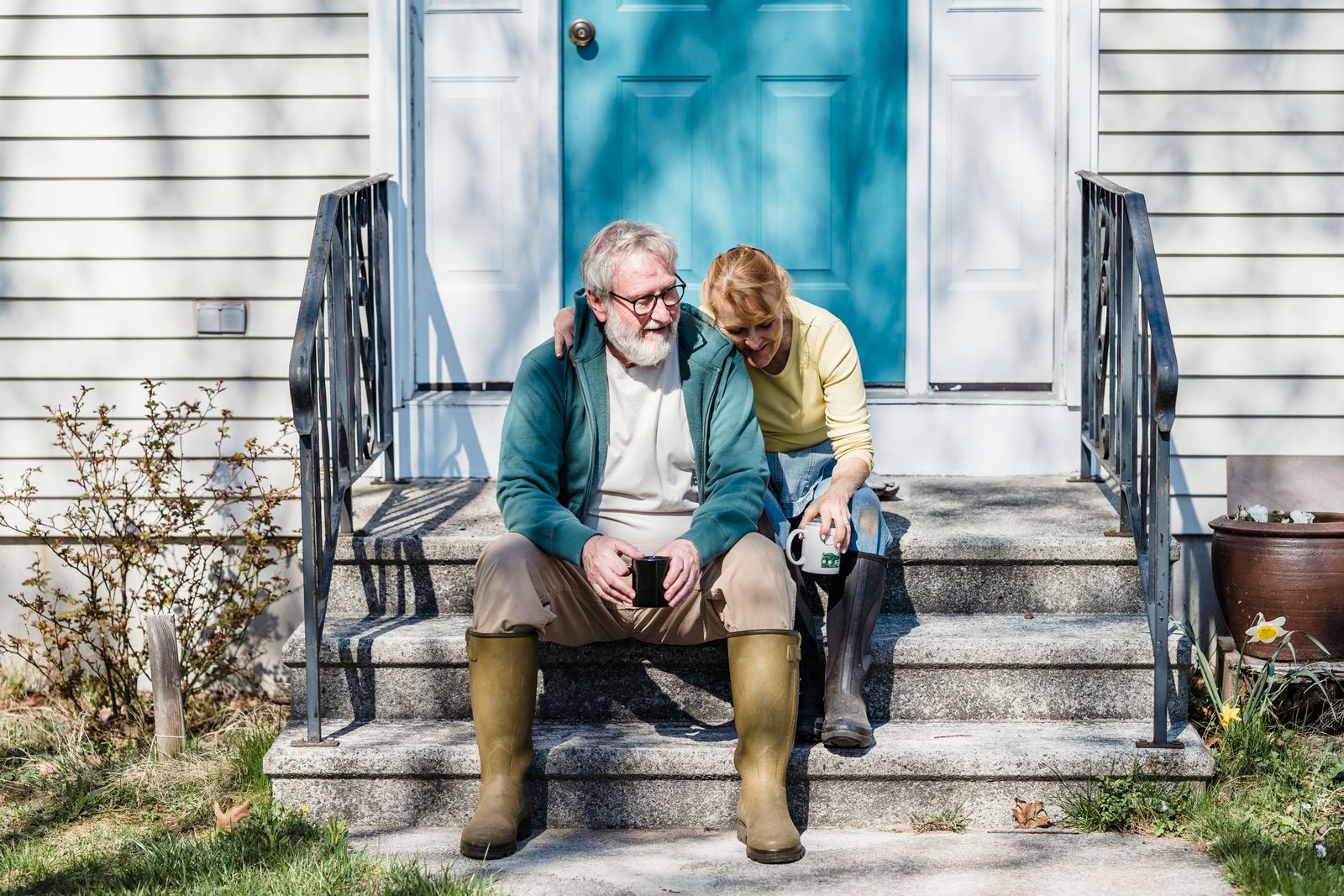 Retirement and home planning Older couple sitting together on the front steps of a home.